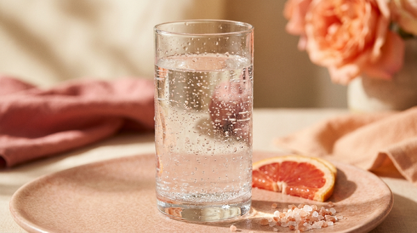 A tall glass of sparkling electrolyte water with a fresh citrus slice and mineral salt